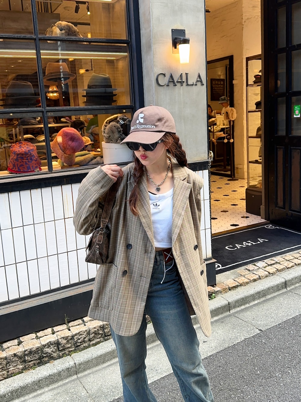 ホワイト系のタンクトップ、ブルー系のデニムパンツ、ホワイト系のスニーカーを着用したレディースの秋コーディネートの4枚目の写真