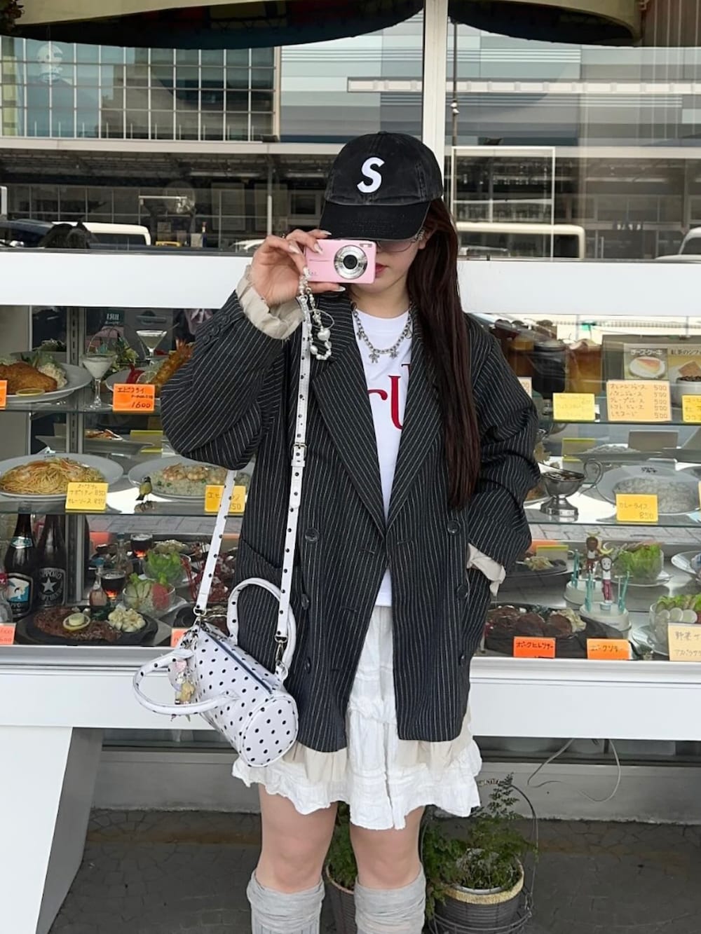 グレー系のテーラードジャケット、ホワイト系のスカート、レッド系のスニーカーを着用したレディースの春コーディネートの3枚目の写真