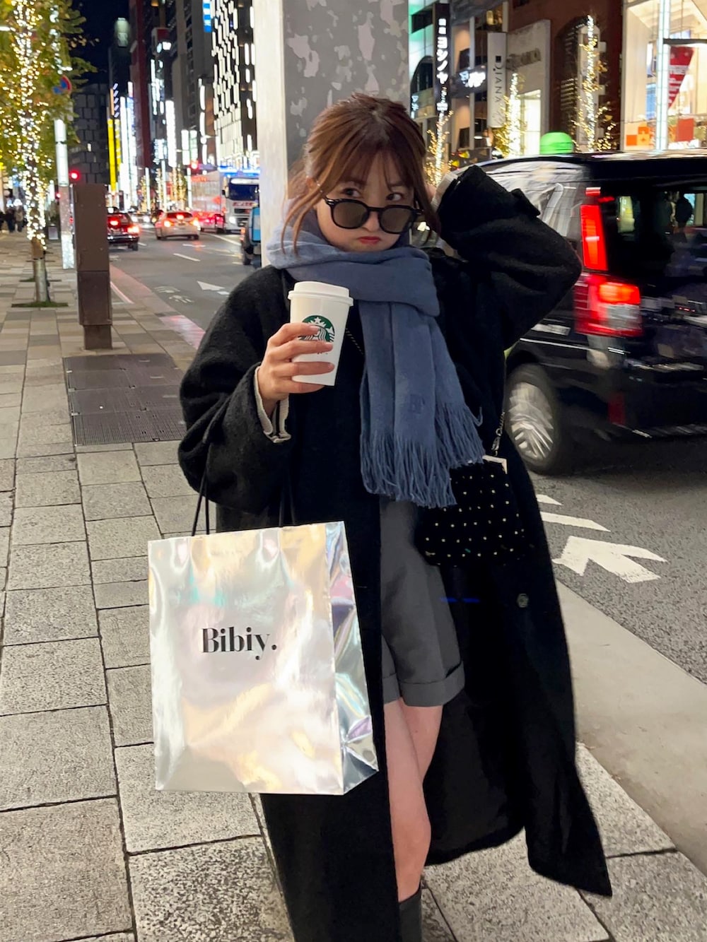 ブラック系のステンカラーコート、ブラック系のブーツ、ブラック系のバッグを着用したレディースの冬コーディネートの4枚目の写真