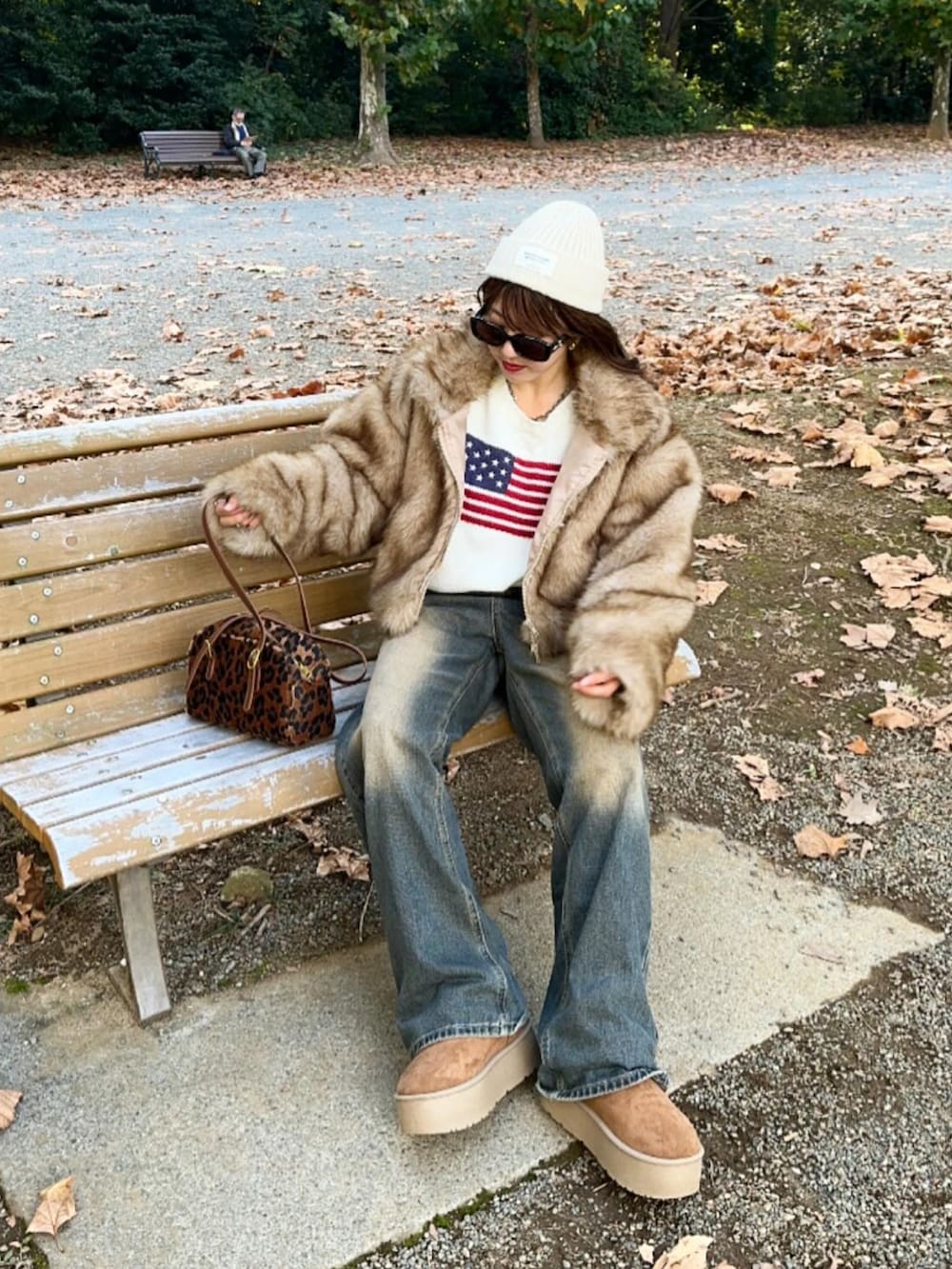 ブラウン系のブルゾン、ホワイト系のニット/セーター、ブルー系のデニムパンツを着用したレディースの秋コーディネートの4枚目の写真