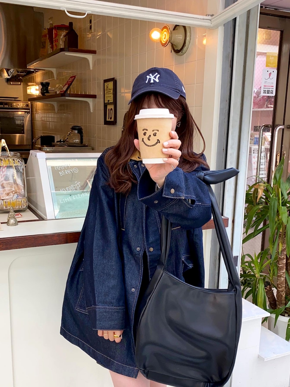 ホワイト系のスニーカー、ブルー系のデニムジャケット、ブルー系のキャップを着用したレディースの秋コーディネートの3枚目の写真