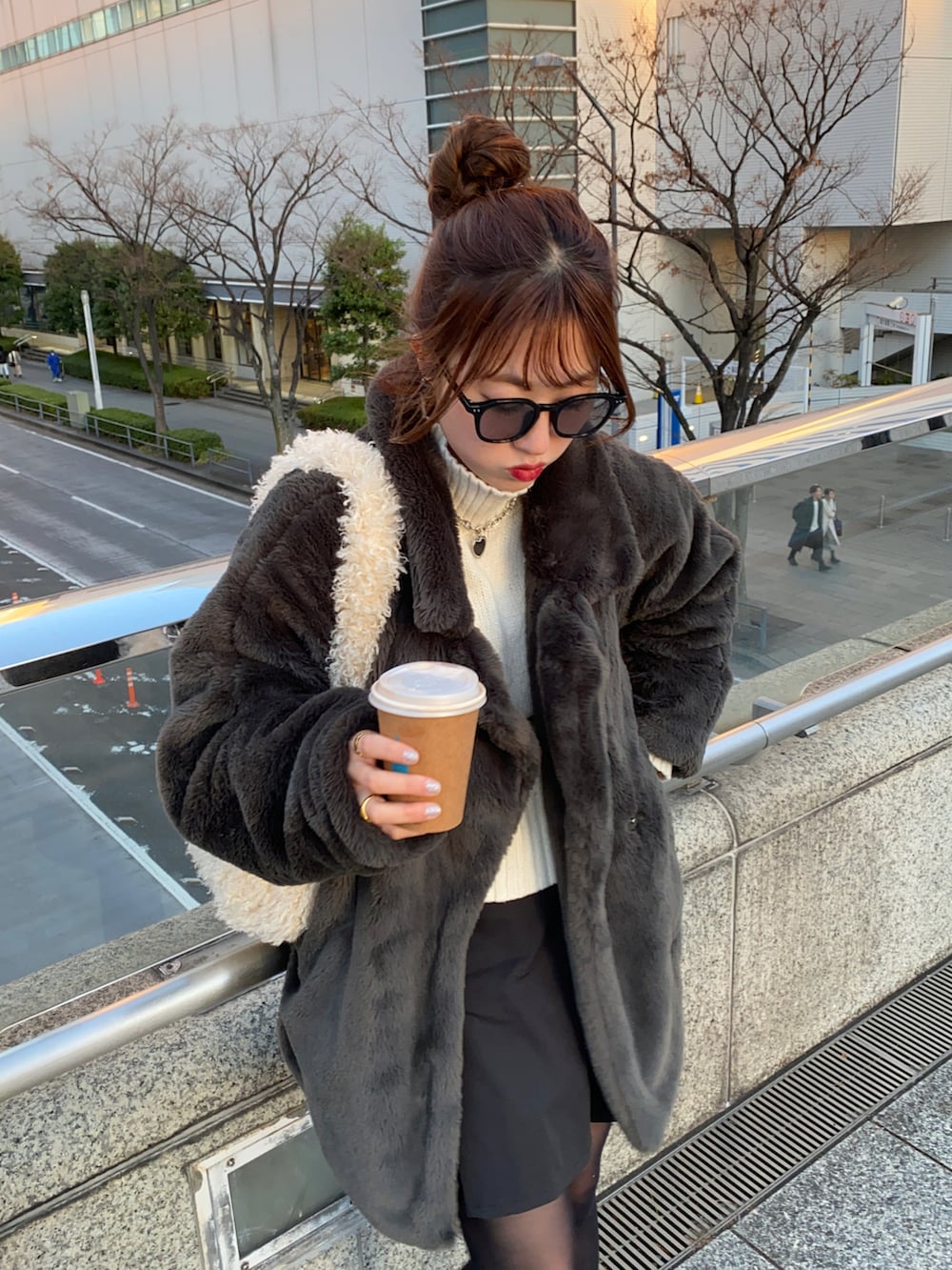 ホワイト系のショルダーバッグ、ホワイト系のスニーカー、ブラック系のスカートを着用したレディースの冬コーディネートの2枚目の写真