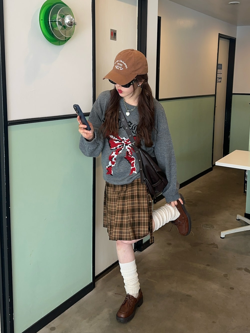 グリーン系のスカート、グレー系のニット/セーター、ブラウン系のシューズを着用したレディースの冬コーディネートの3枚目の写真