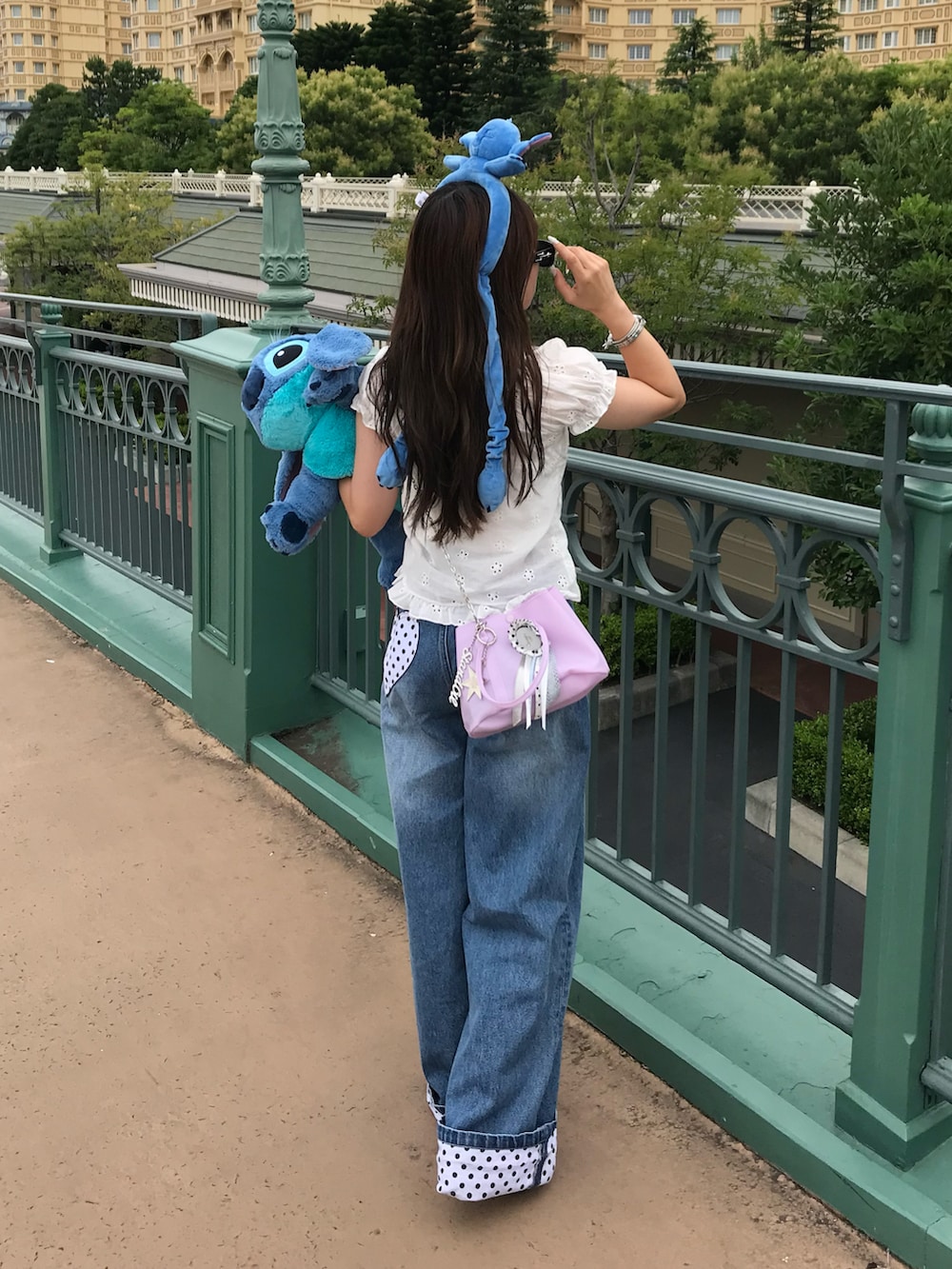 ブルー系のパンツ、パープル系のバッグ、シルバー系のシューズを着用したレディースの夏コーディネートの2枚目の写真