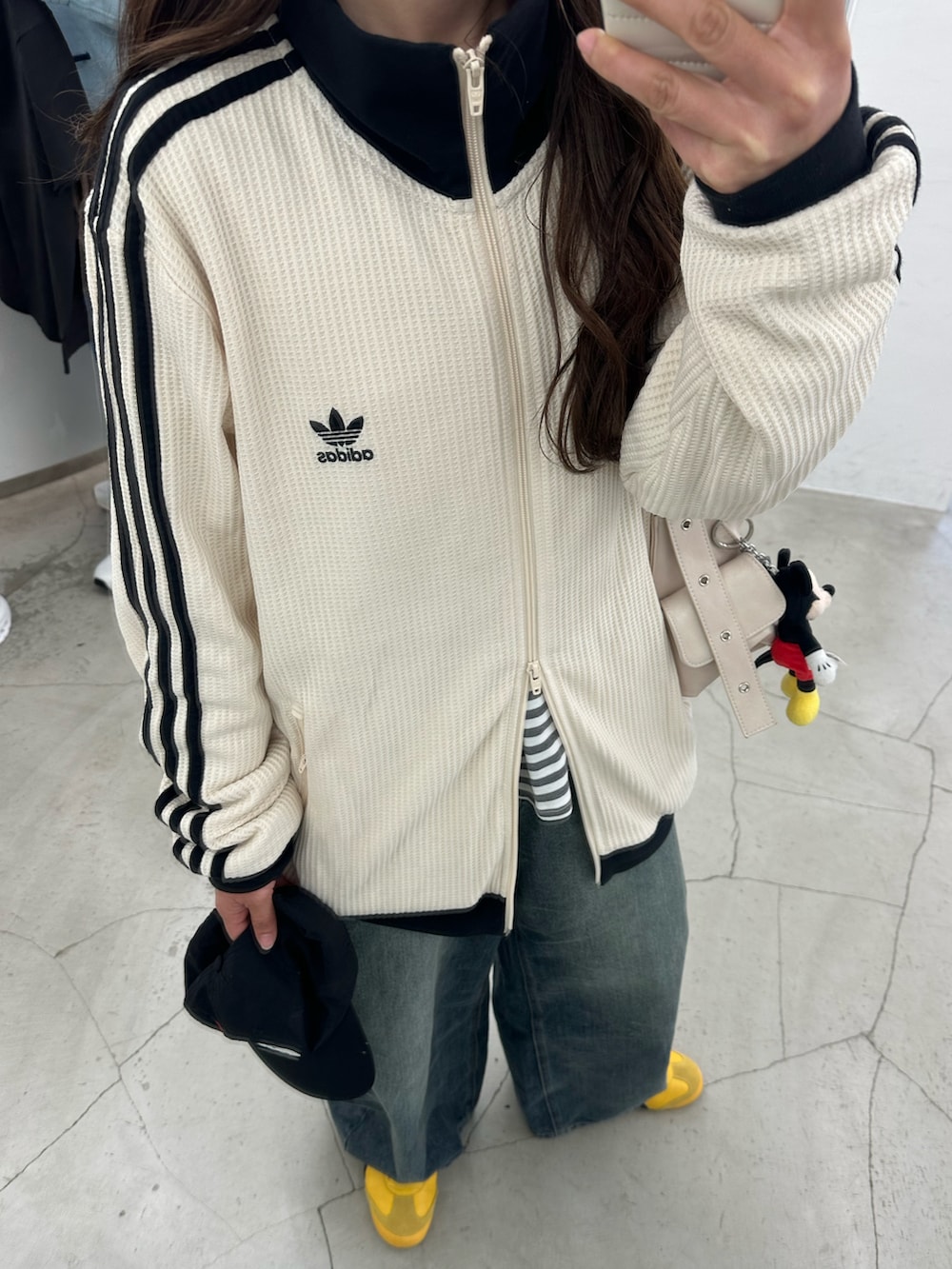 ホワイト系のジャージ、ブルー系のデニムパンツ、イエロー系のスニーカーを着用したレディースの春コーディネートの4枚目の写真