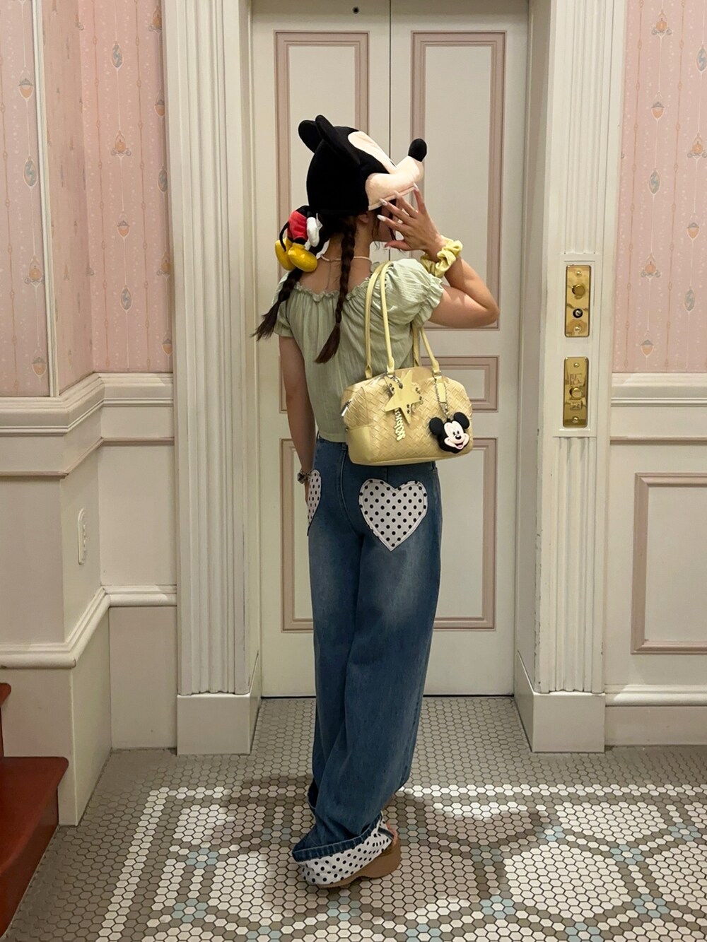 グリーン系のトップス、ブルー系のデニムパンツ、イエロー系のバッグを着用したレディースの夏コーディネートの2枚目の写真