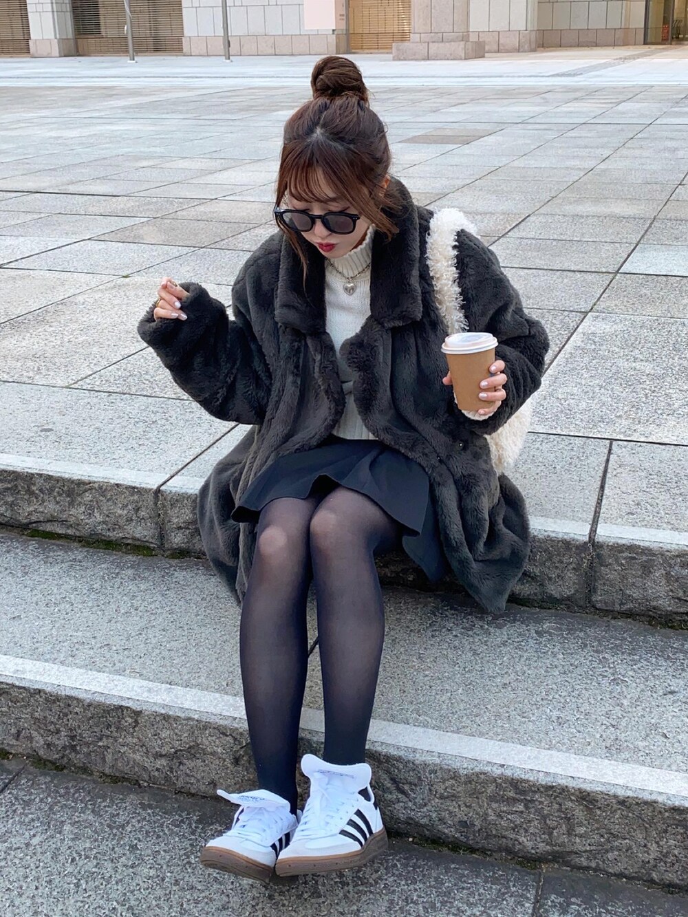 ホワイト系のショルダーバッグ、ホワイト系のスニーカー、ブラック系のスカートを着用したレディースの冬コーディネートの3枚目の写真