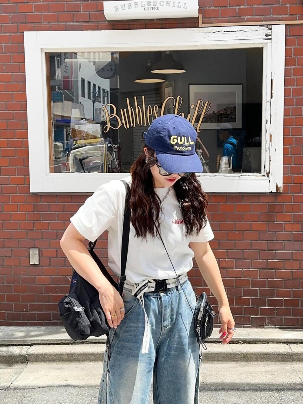 ブラック系のバックパック/リュック、ホワイト系のTシャツ/カットソー、ブルー系のキャップを着用したレディースの春コーディネートの3枚目の写真