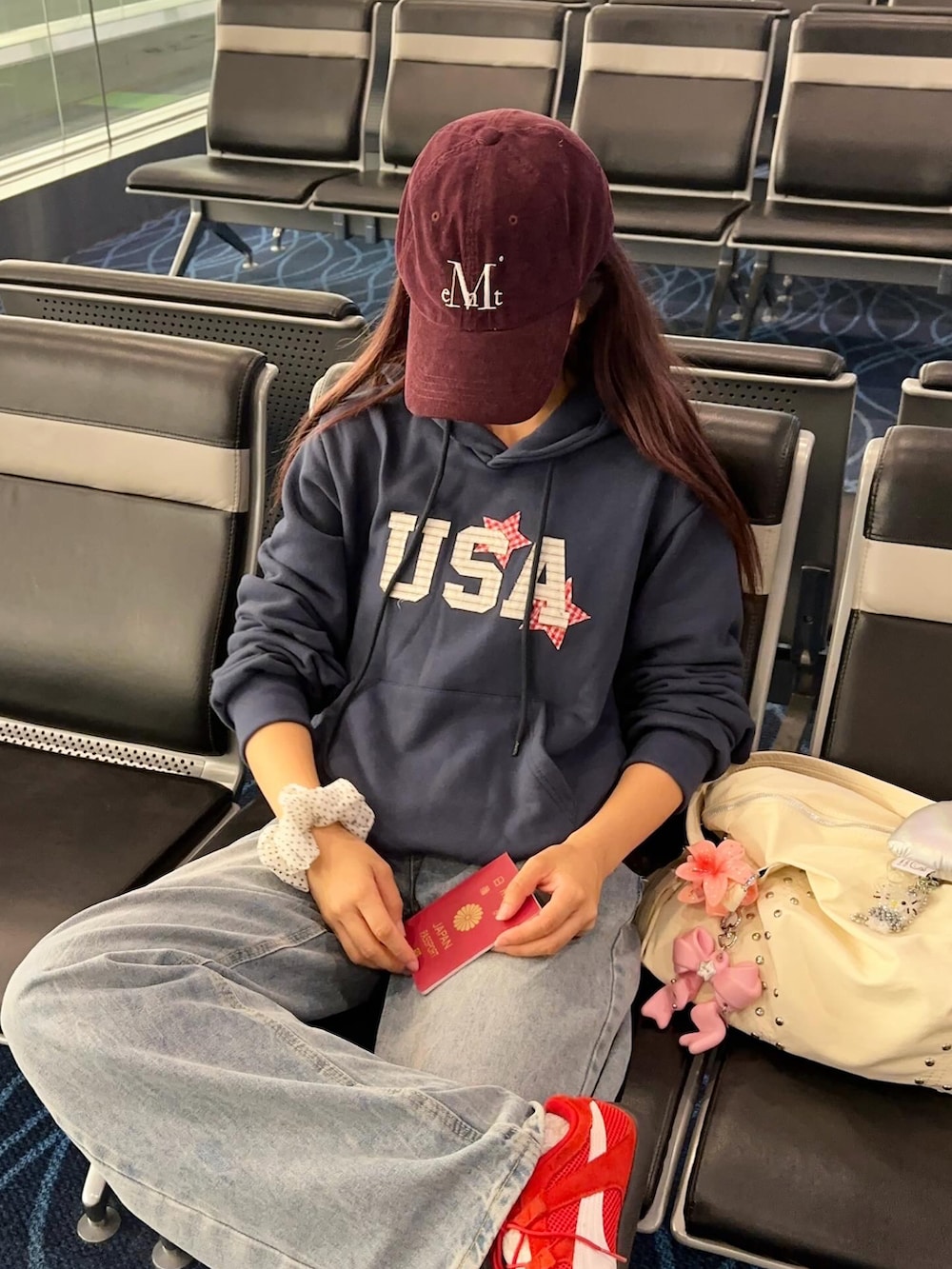 レッド系のスニーカー、ホワイト系のショルダーバッグ、ブルー系のパーカーを着用したレディースの秋コーディネートの2枚目の写真