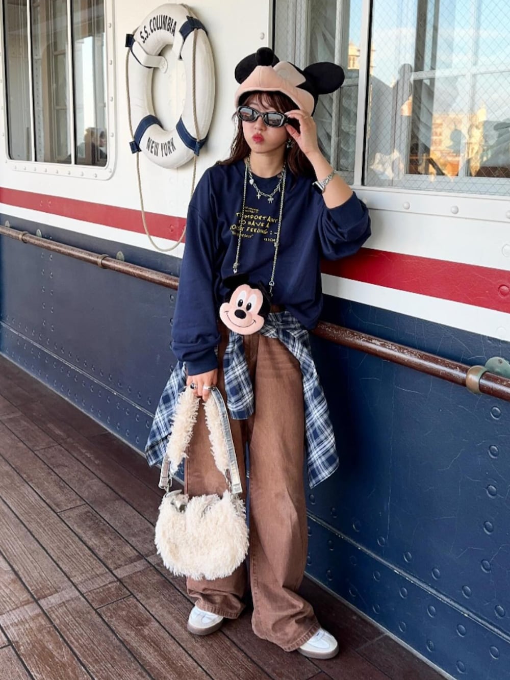 ブルー系のスウェット、ブラック系のデニムパンツ、ブラウン系のショルダーバッグを着用したレディースの秋コーディネートの3枚目の写真