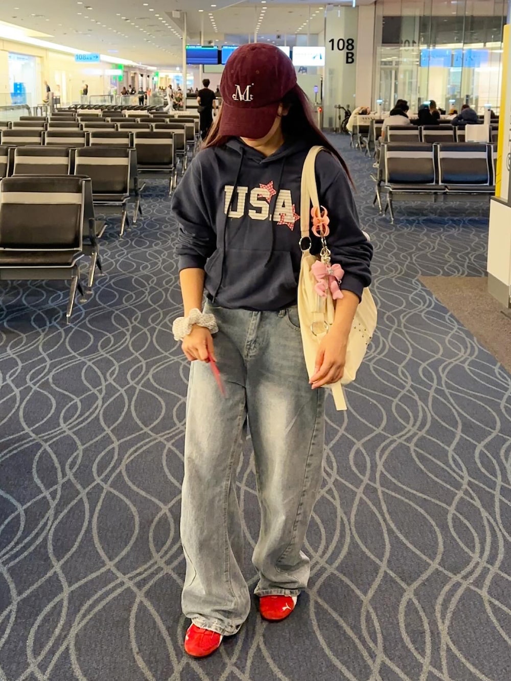 レッド系のスニーカー、ホワイト系のショルダーバッグ、ブルー系のパーカーを着用したレディースの秋コーディネートの3枚目の写真