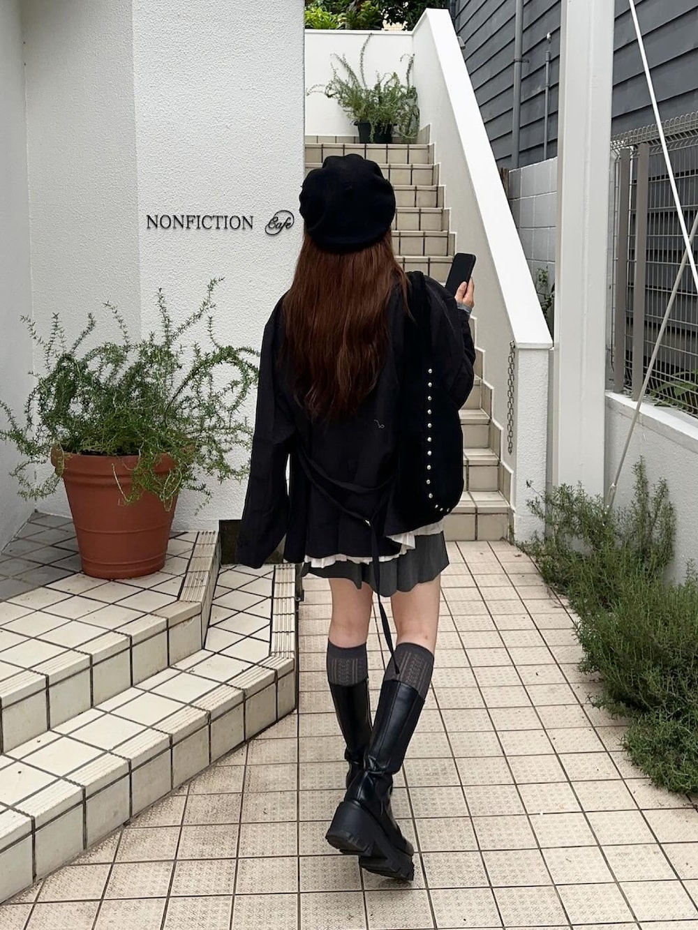 ブラック系のテーラードジャケット、ブラック系のブーツ、グレー系のスカートを着用したレディースの秋コーディネートの2枚目の写真