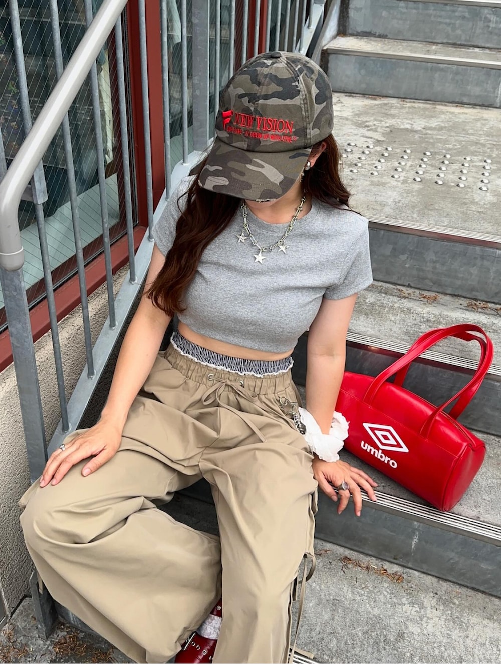 レッド系のボストンバッグ、レッド系のパンプス、グレー系のTシャツ/カットソーを着用したレディースの夏コーディネートの2枚目の写真