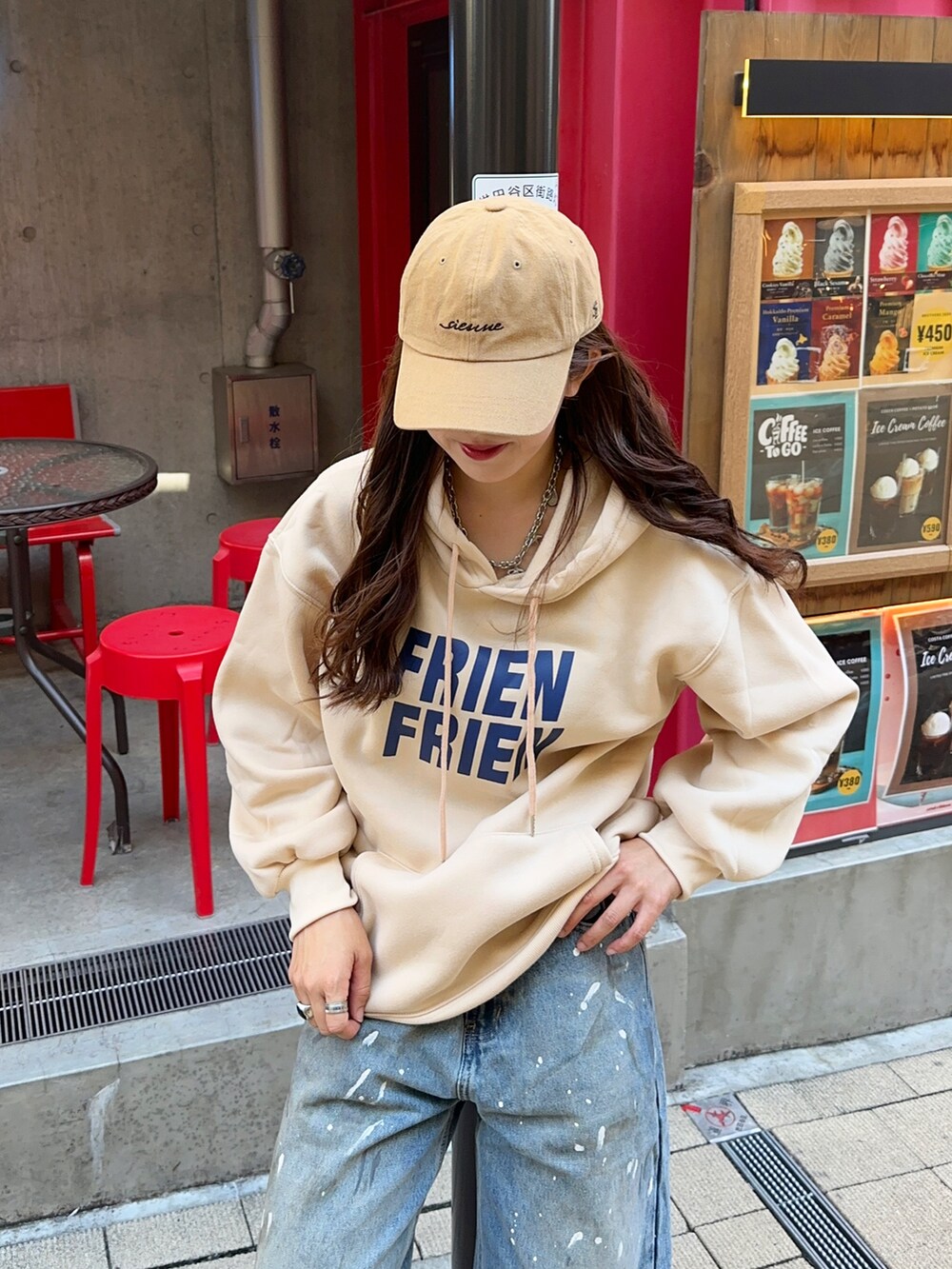 ブルー系のデニムパンツ、ホワイト系のスニーカー、ベージュ系のキャップを着用したレディースの秋コーディネートの2枚目の写真