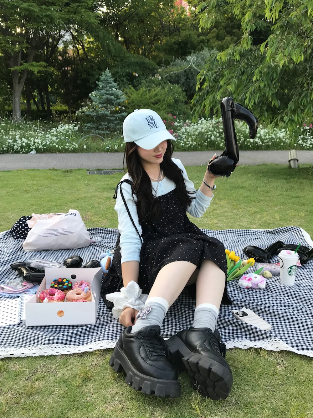 ブラック系のワンピース/ドレス、ブラック系のスニーカー、ブルー系のキャップを着用したレディースの春コーディネートの2枚目の写真