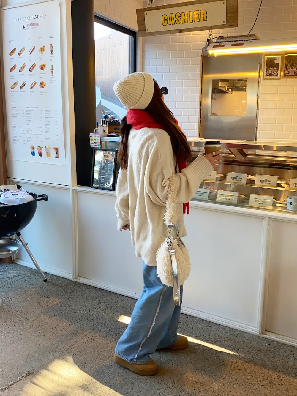 ブルー系のデニムパンツ、ベージュ系のスニーカー、ホワイト系のショルダーバッグを着用したレディースの冬コーディネートの3枚目の写真