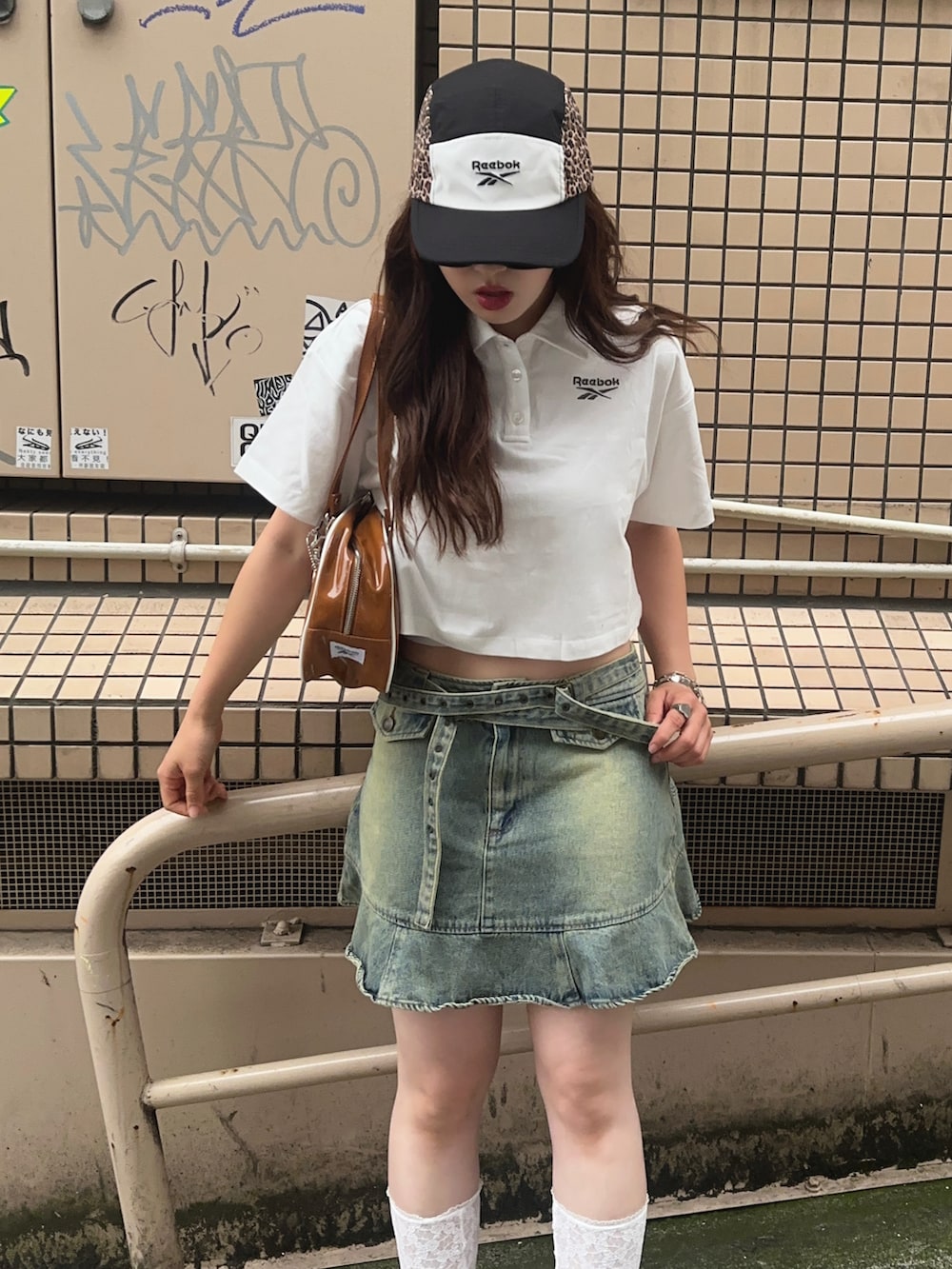 ホワイト系のサンダル、ブラウン系のボストンバッグ、ブルー系のデニムスカートを着用したレディースの春コーディネートの3枚目の写真