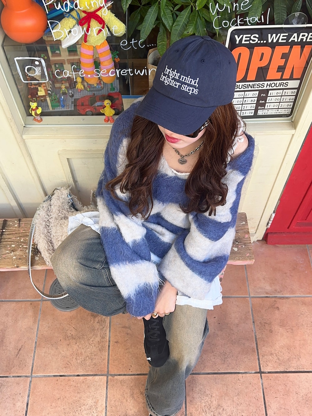 ブルー系のニット/セーター、ブラック系のスニーカー、レッド系のショルダーバッグを着用したレディースの冬コーディネートの2枚目の写真