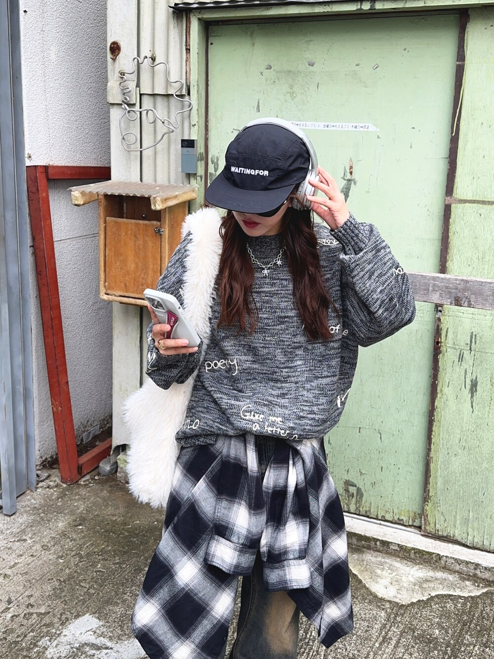 グレー系のニット/セーター、ブルー系のデニムパンツ、ブラック系のシャツ/ブラウスを着用したレディースの秋コーディネートの2枚目の写真