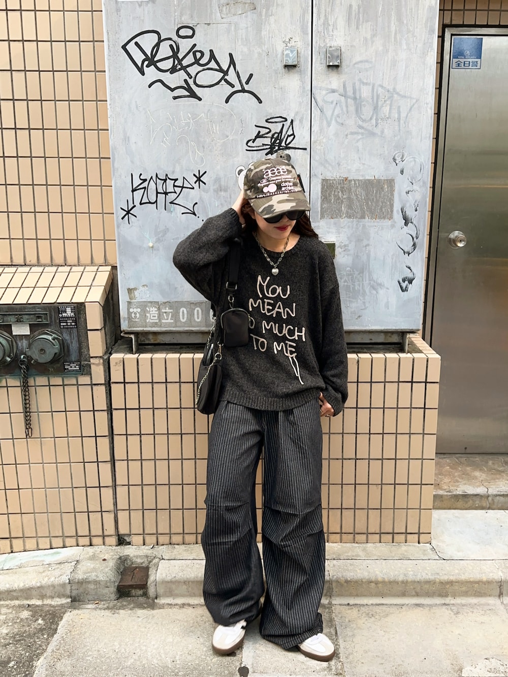 ブラック系のデニムパンツ、ホワイト系のスニーカー、グレー系のニット/セーターを着用したレディースの秋コーディネートの3枚目の写真