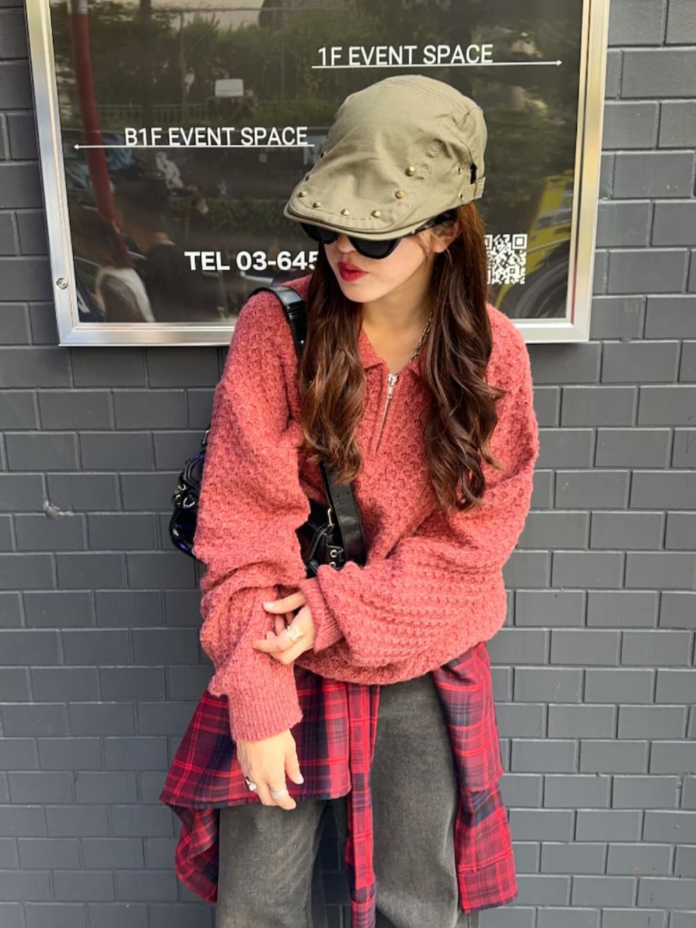 レッド系のニット/セーター、レッド系のスカート、ブラック系のデニムパンツを着用したレディースの秋コーディネートの2枚目の写真