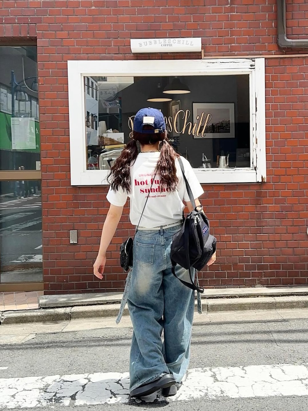 ブラック系のバックパック/リュック、ホワイト系のTシャツ/カットソー、ブルー系のキャップを着用したレディースの春コーディネートの2枚目の写真