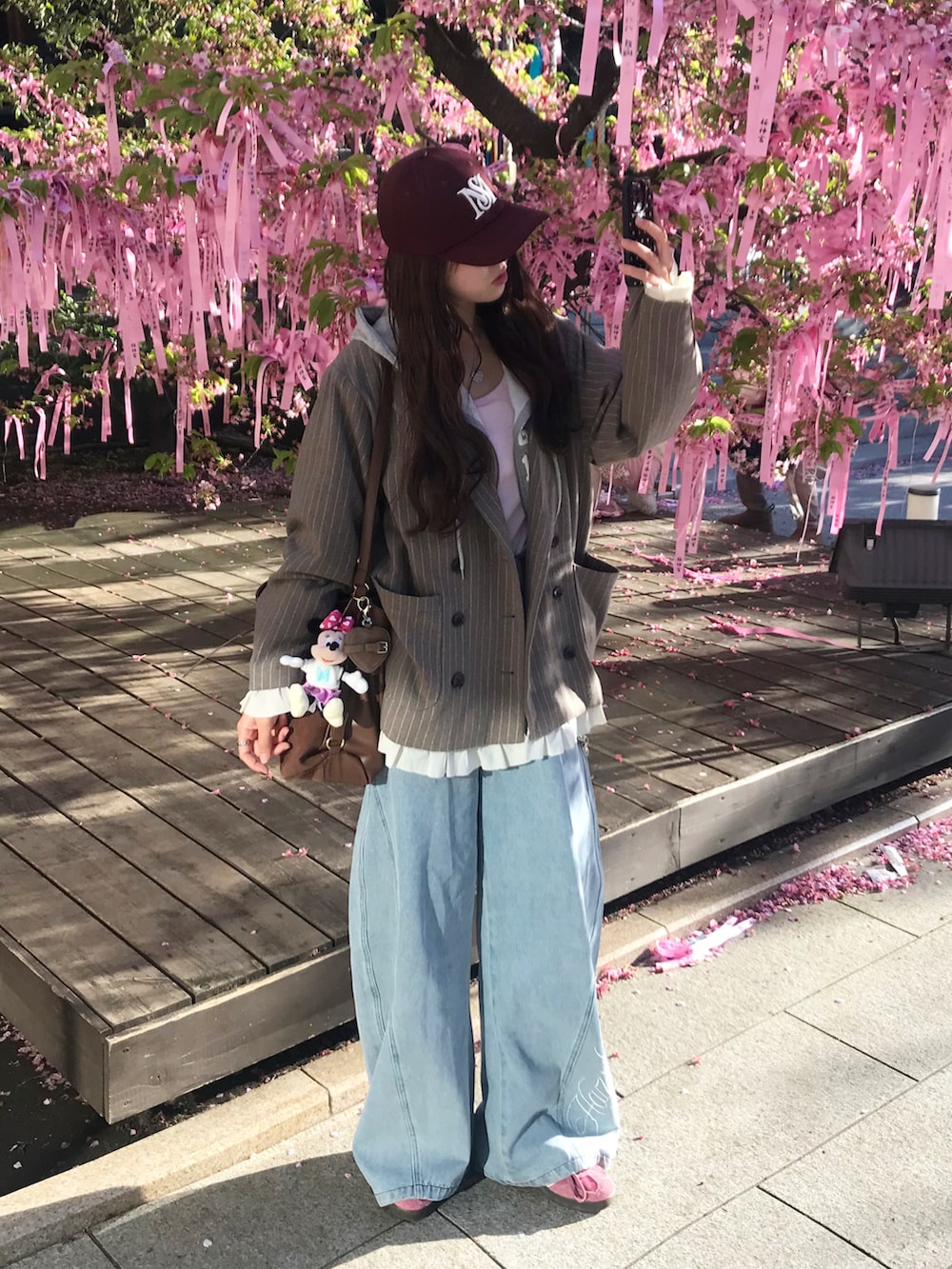 ブラウン系のテーラードジャケット、ブルー系のデニムパンツ、ホワイト系のスニーカーを着用したレディースの春コーディネートの2枚目の写真