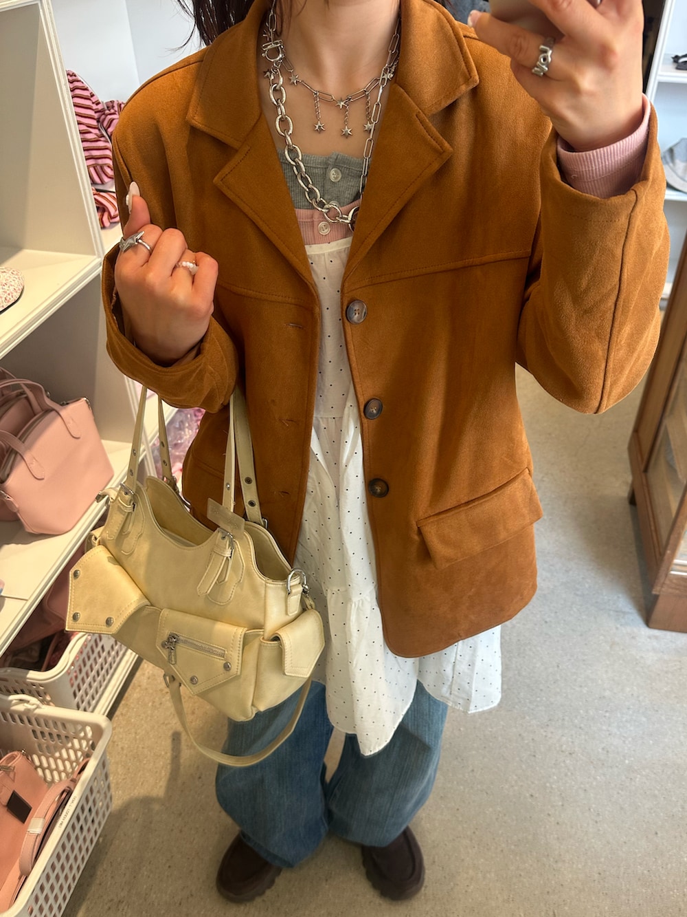 ベージュ系のテーラードジャケット、ブラウン系のローファー、ブルー系のデニムパンツを着用したレディースの春コーディネートの2枚目の写真