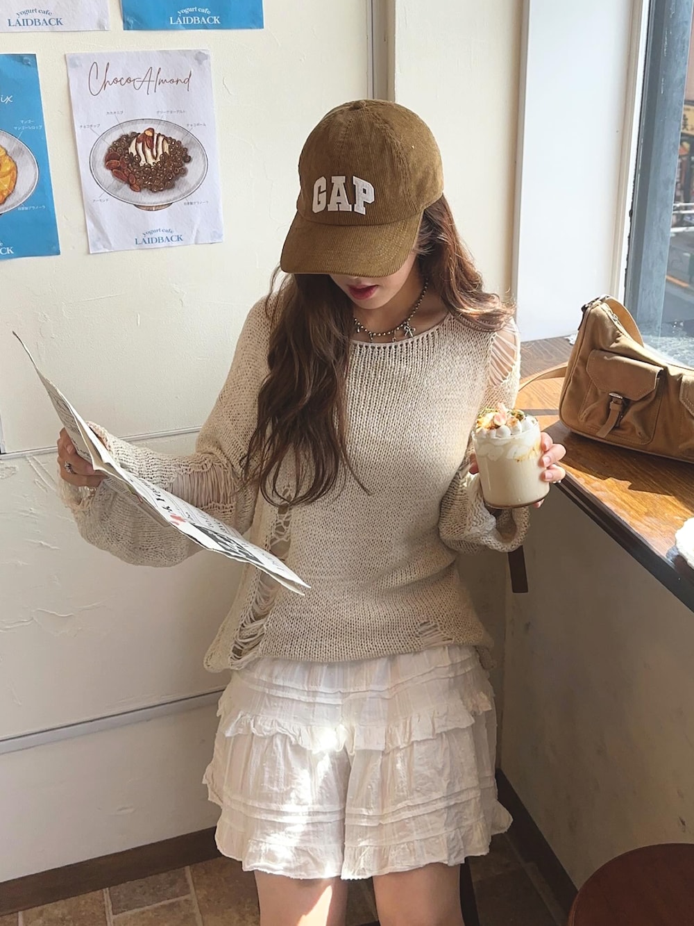 イエロー系のハンドバッグ、ブラウン系のブーツ、ベージュ系のニット/セーターを着用したレディースの秋コーディネートの2枚目の写真