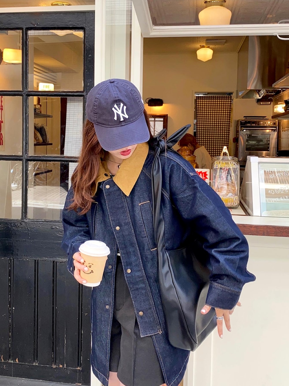 ホワイト系のスニーカー、ブルー系のデニムジャケット、ブルー系のキャップを着用したレディースの秋コーディネートの5枚目の写真