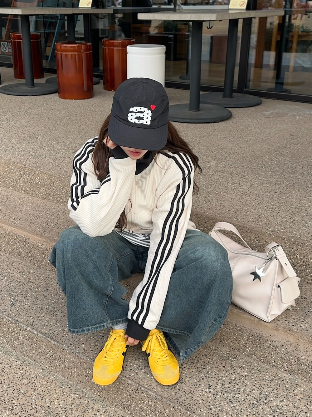 ホワイト系のジャージ、ブルー系のデニムパンツ、イエロー系のスニーカーを着用したレディースの春コーディネートの2枚目の写真