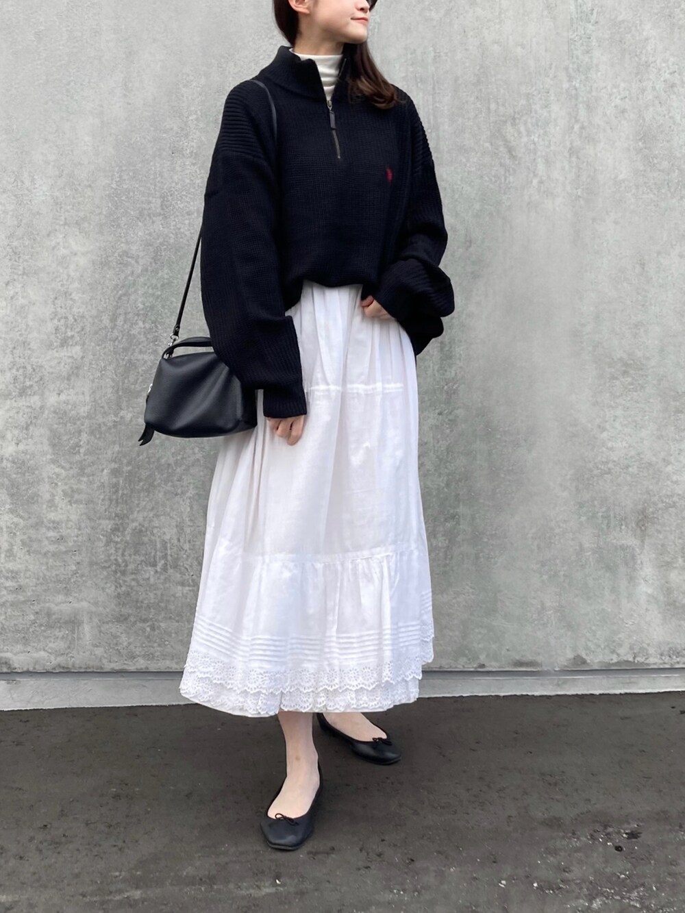 ブルー系のニット/セーター、ホワイト系のスカート、ブラック系のショルダーバッグを着用したレディースの冬コーディネートの2枚目の写真