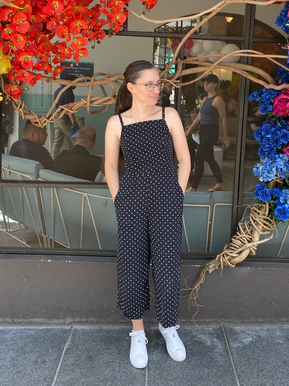 ブラック系のオールインワン・サロペット、ホワイト系のスニーカーを着用したレディースの春コーディネートの2枚目の写真