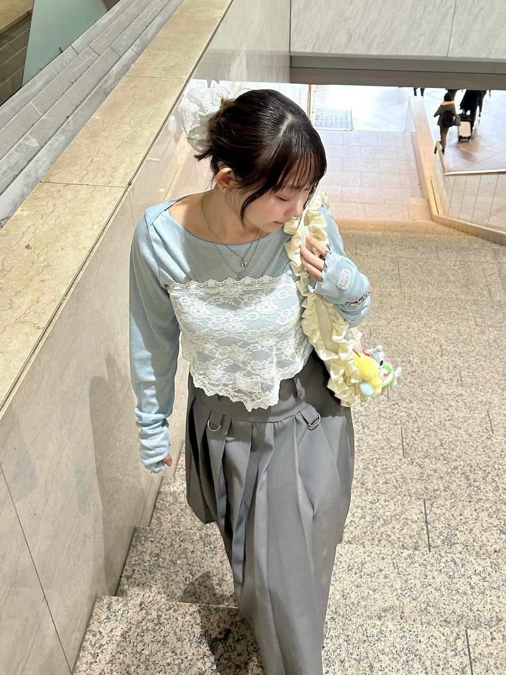 グレー系のスカート、ホワイト系のハンドバッグ、ホワイト系のスニーカーを着用したレディースの冬コーディネートの2枚目の写真