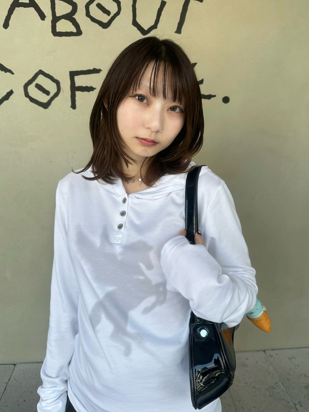 ホワイト系のTシャツ/カットソー、ブラック系のハンドバッグ、ブラック系のスカートを着用したレディースの春コーディネートの2枚目の写真
