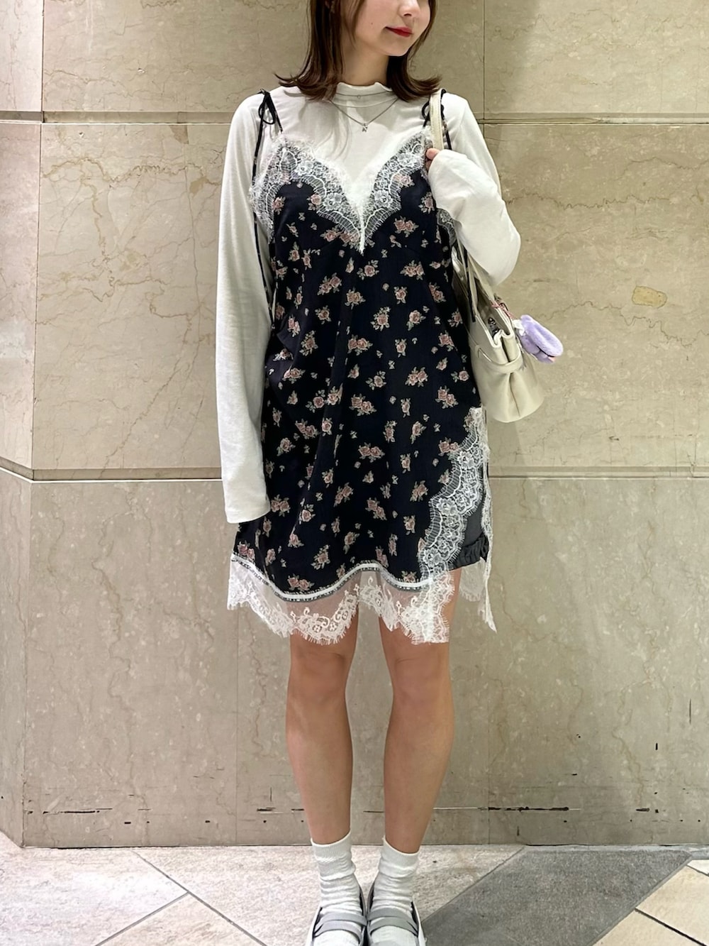 グレー系のスニーカー、ブラック系のワンピース、ホワイト系のショルダーバッグを着用したレディースの冬コーディネートの2枚目の写真