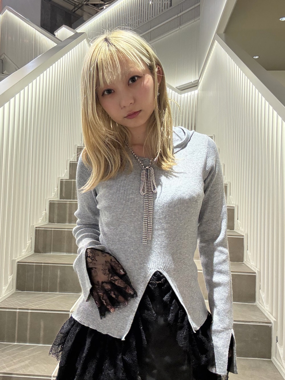 グレー系のパーカー、ブラック系のスカートを着用したレディースの秋コーディネートの2枚目の写真