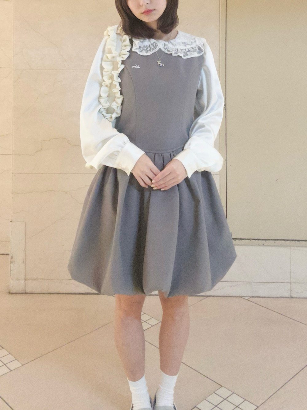 グレー系のジャンパースカート、ホワイト系のシャツ/ブラウス、ホワイト系のハンドバッグを着用したレディースの春コーディネートの2枚目の写真