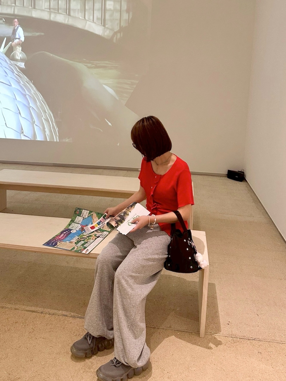 レッド系のニット/セーター、グレー系のスウェットパンツ、グレー系のスニーカーを着用したレディースの夏コーディネートの2枚目の写真