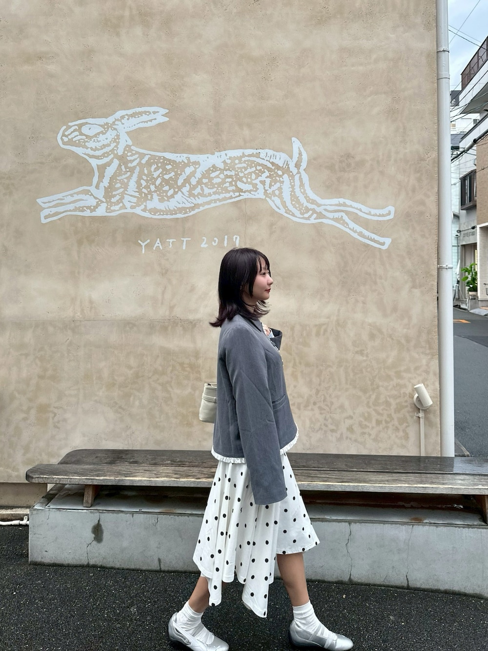 グレー系のテーラードジャケット、グレー系のスニーカー、ホワイト系のスカートを着用したレディースの春コーディネートの2枚目の写真