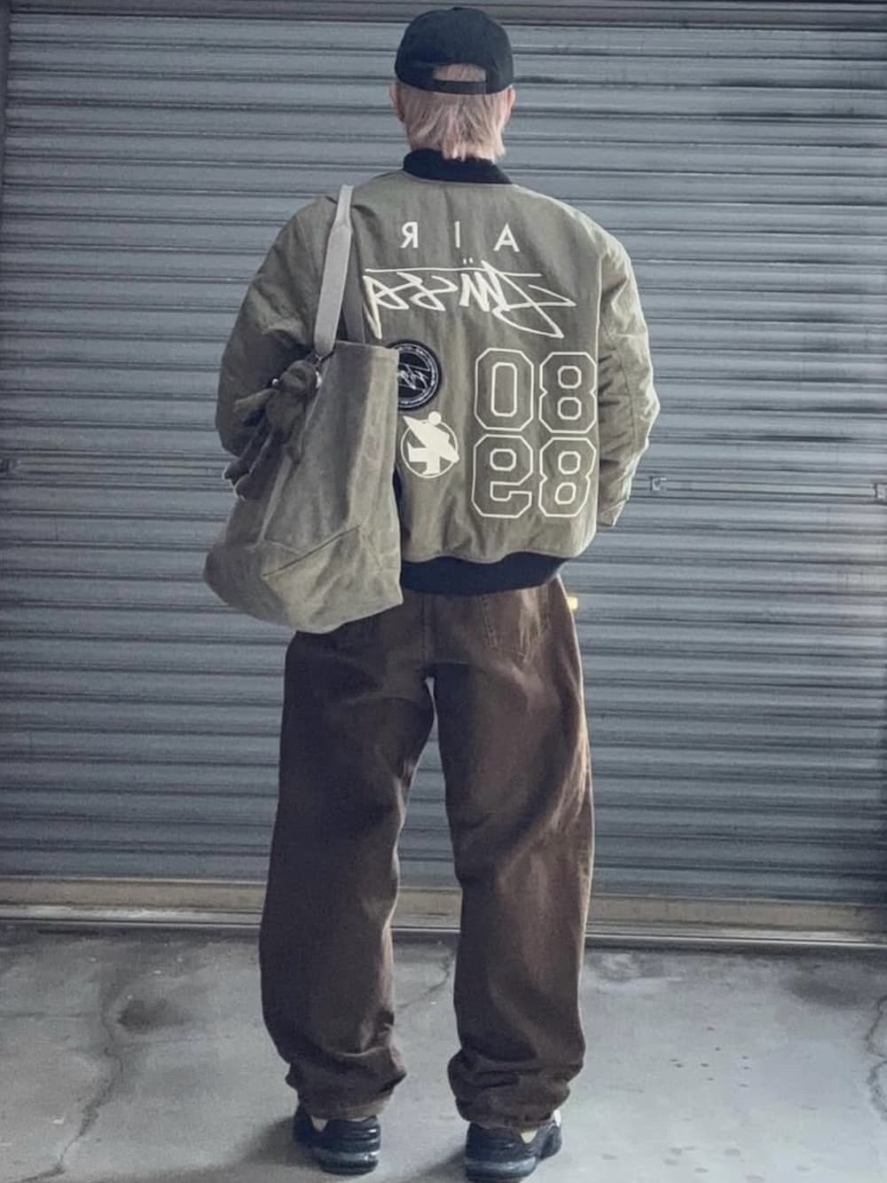 グリーン系のMA-1、ブラック系のTシャツ/カットソー、ブラウン系のデニムパンツを着用したメンズの冬コーディネートの4枚目の写真