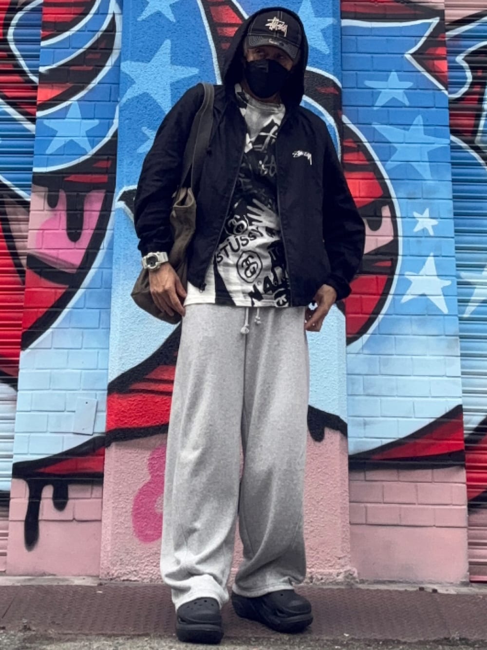 グレー系のスウェットパンツ、ブラック系のナイロンジャケット、ブラック系のサンダルを着用したメンズの冬コーディネートの2枚目の写真