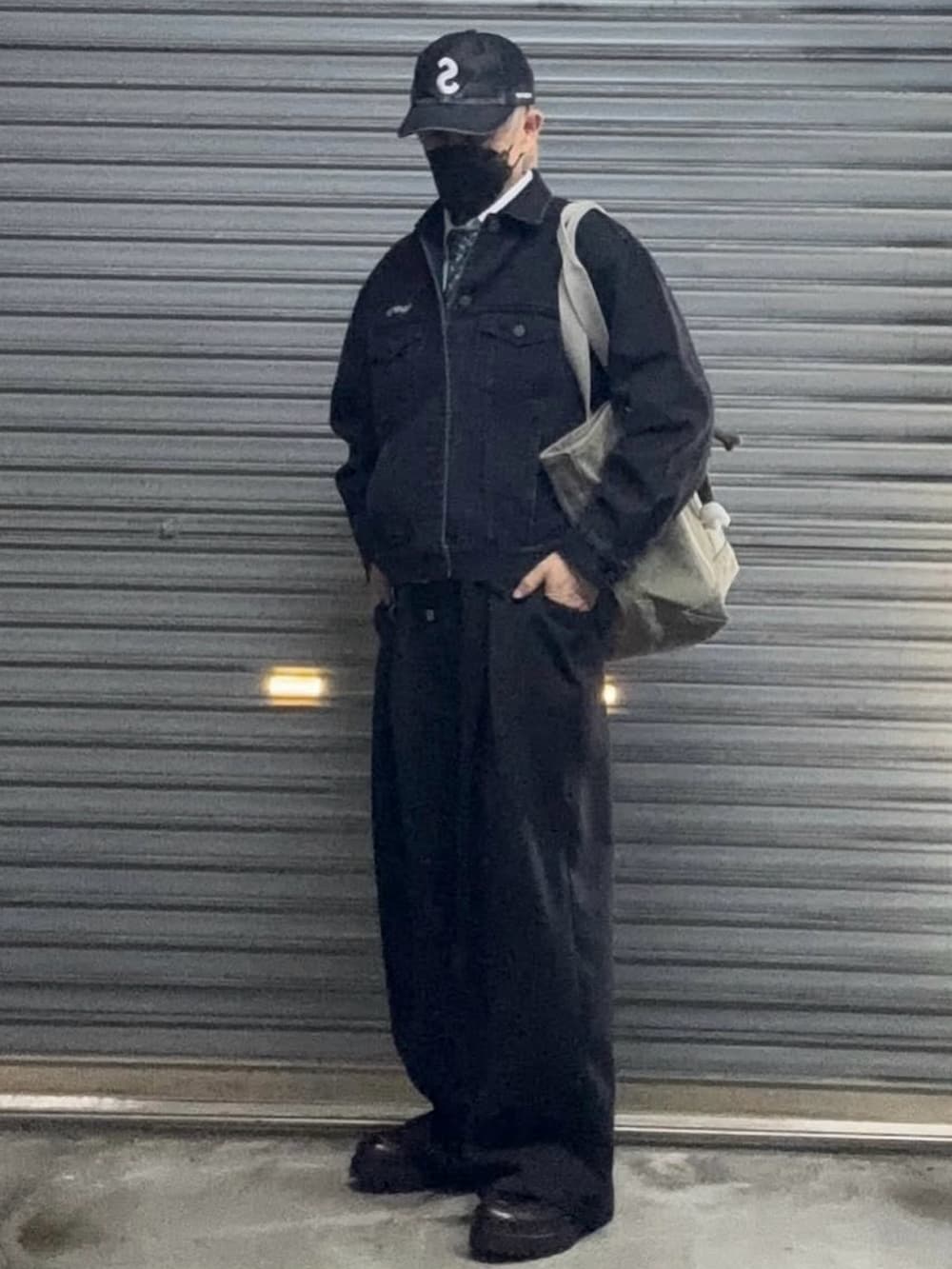 ブラック系のスラックス、ブラック系のデニムジャケット、ブラック系のキャップを着用したメンズの冬コーディネートの2枚目の写真