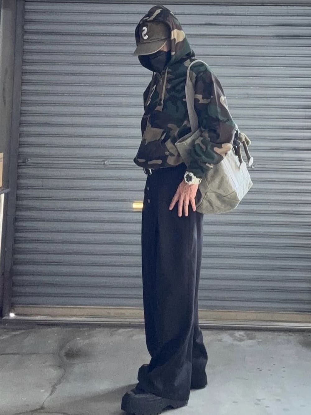 ベージュ系のパーカー、ブラック系のスラックス、ベージュ系のキャップを着用したメンズの冬コーディネートの2枚目の写真