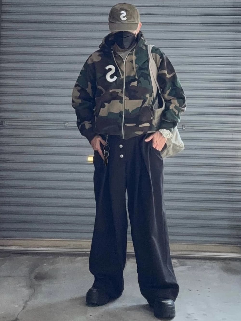 ベージュ系のパーカー、ブラック系のスラックス、ベージュ系のキャップを着用したメンズの冬コーディネートの3枚目の写真