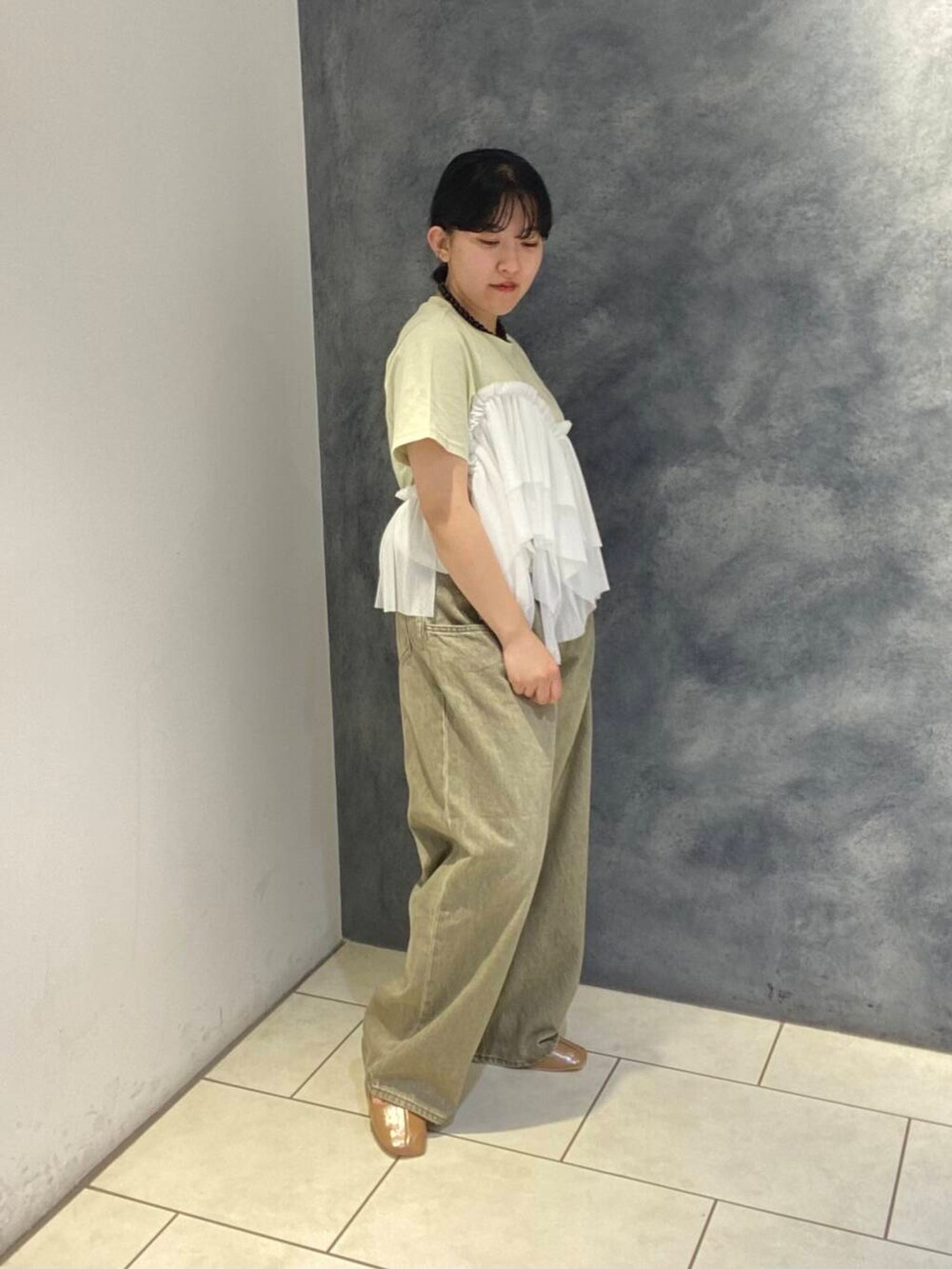 イエロー系のパンプス、グリーン系のTシャツ/カットソー、グリーン系のデニムパンツを着用したレディースの春コーディネートの2枚目の写真