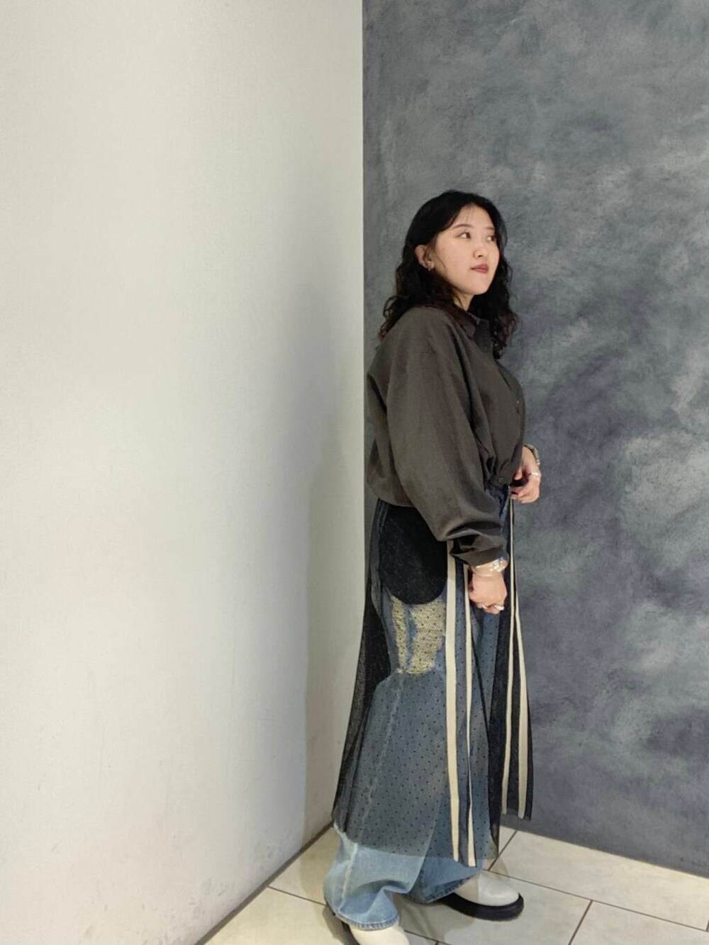 ブルー系のデニムパンツ、ブラウン系のシャツ/ブラウス、ブラック系のスカートを着用したレディースの秋コーディネートの3枚目の写真
