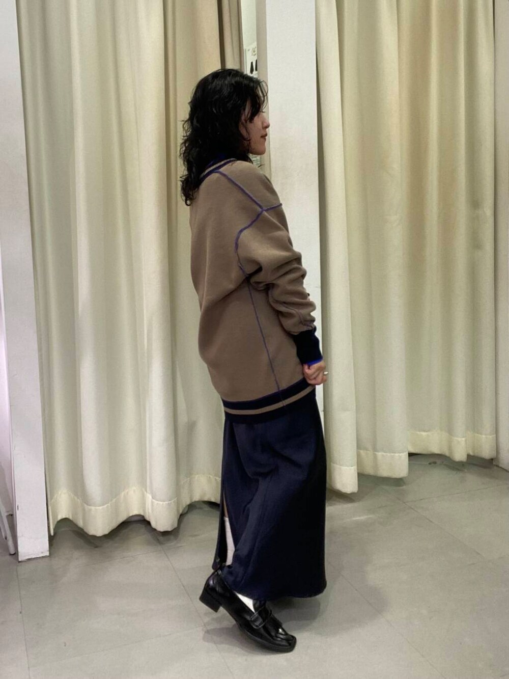 ブルー系のスカート、ブラック系のローファー、ブルー系のTシャツ/カットソーを着用したレディースの秋コーディネートの4枚目の写真