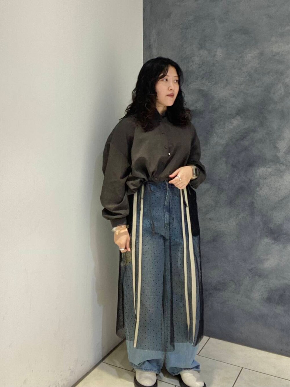 ブルー系のデニムパンツ、ブラウン系のシャツ/ブラウス、ブラック系のスカートを着用したレディースの秋コーディネートの2枚目の写真