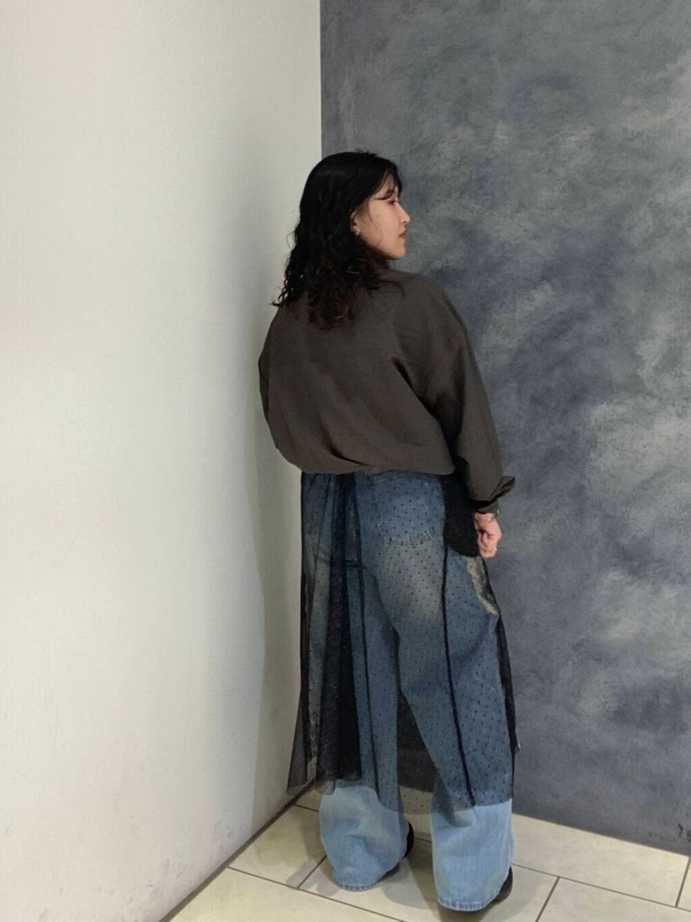 ブルー系のデニムパンツ、ブラウン系のシャツ/ブラウス、ブラック系のスカートを着用したレディースの秋コーディネートの4枚目の写真